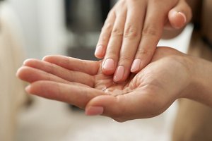 Woman with manicured hands smoothing argan oil over her palms